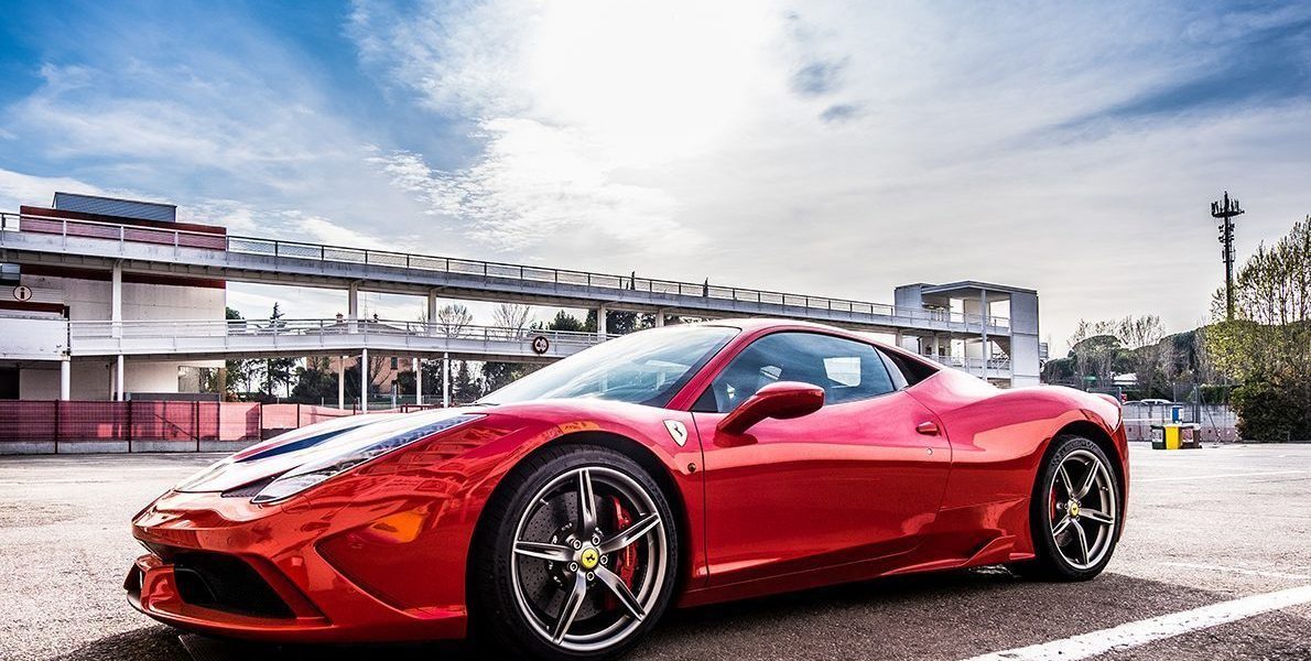 Rød Ferrari parkeret udenfor i sommervejr