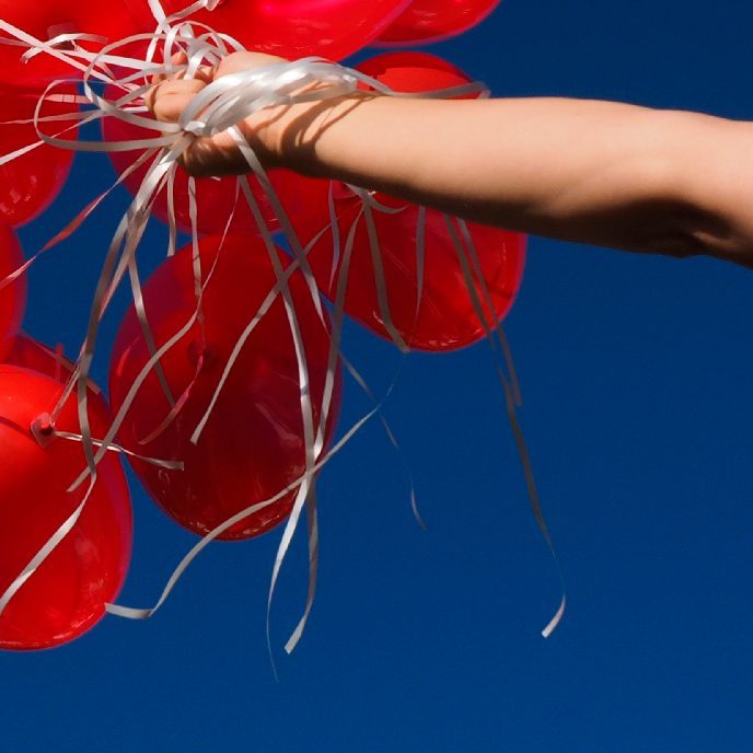 arm der holder røde balloner mod in blå himmel