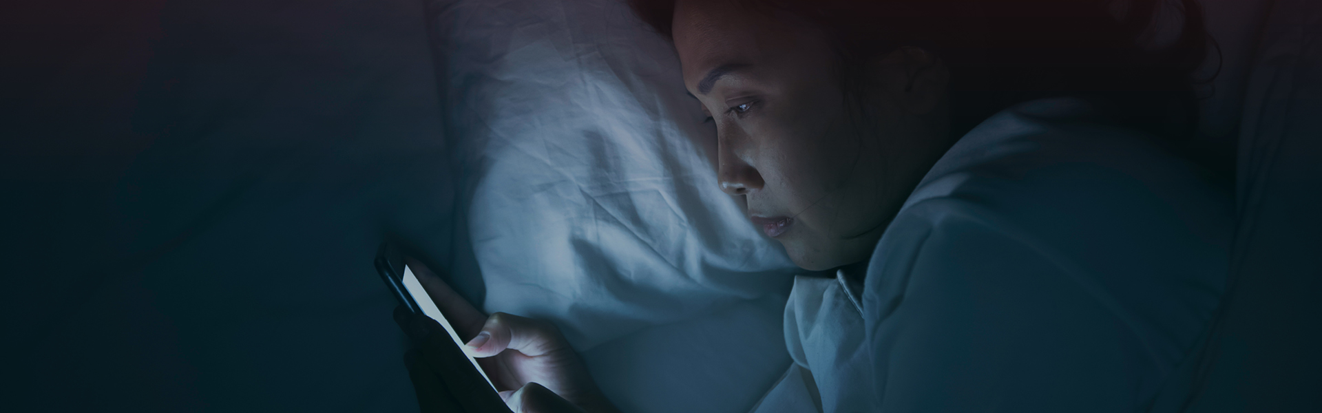 Kvinde i seng med telefon